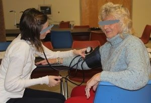 Employee having blood pressure measured through sweater at onsite biometric screening